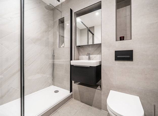 Bathroom with shower enclosure, vanity unit, mirror and wall-mounted cabinet.