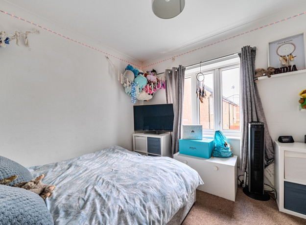 Bedroom with double bed, television, window and storage units.