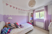 Children bedroom with bed, toys, purple decor and window.