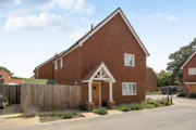 Red brick detached house with driveway, white trim, and fenced front garden.