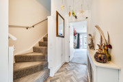 Hallway with carpeted stairs, console table and front door view.