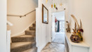 Hallway with carpeted stairs, console table and front door view.