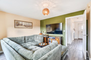 Living room with corner sofa, TV, feature wall and doors into hallway.