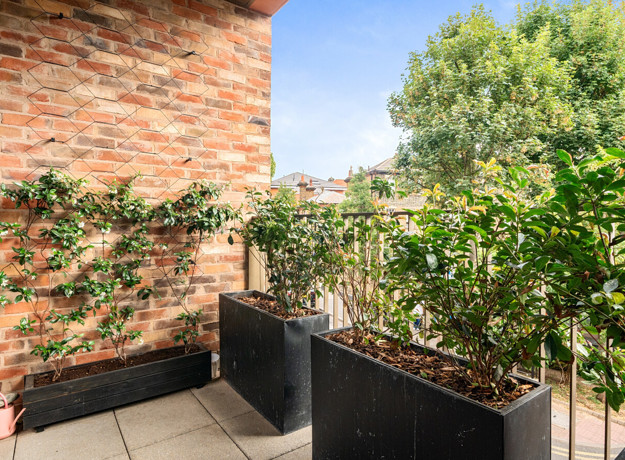 Private balcony with planter boxes, climbing plants and surrounding greenery.