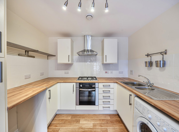 Fitted kitchen with oven, hob, extractor fan and worktops.