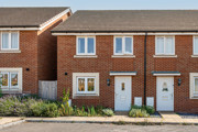 Front elevation of a red brick terraced house with neighbouring properties.