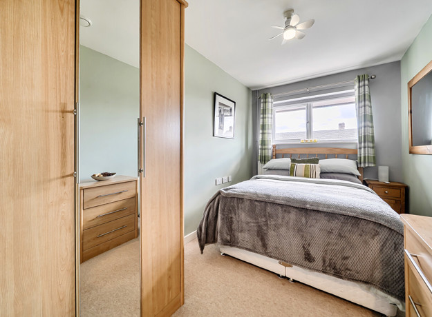 Bedroom with double bed, wardrobe, bedside tables and window.
