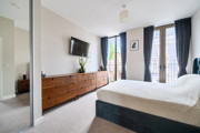 Bedroom with double bed, wall-mounted TV, storage unit and balcony doors.