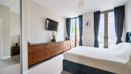 Bedroom with double bed, wall-mounted TV, storage unit and balcony doors.