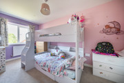 Children’s bedroom with white bunk bed, pink walls, and storage furniture.