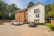 Apartment building with parked cars in front parking area.