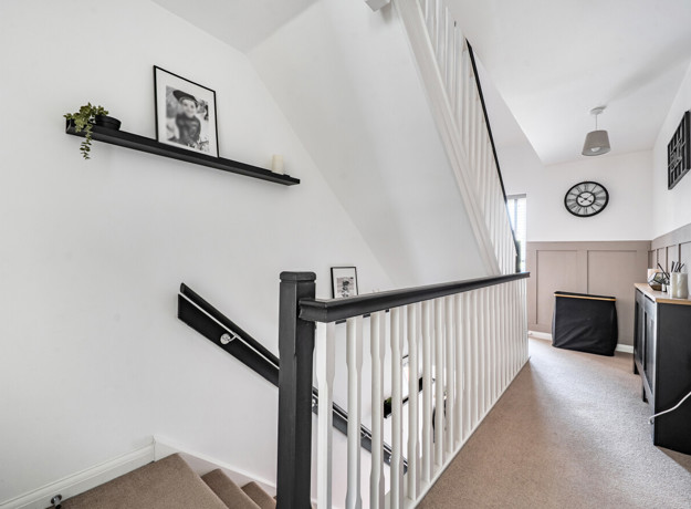 Landing with staircase, wall shelf and doors leading to rooms.