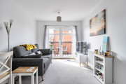 Living room with sofa, television unit and doors leading to balcony.