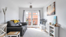 Living room with sofa, television unit and doors leading to balcony.