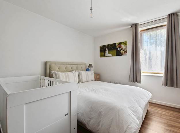 Bedroom with bed, cot, window, and curtains.