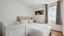 Bedroom with bed, cot, window, and curtains.