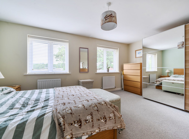 Bedroom with double bed, mirrored wardrobe, and window allowing natural light.