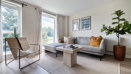 Living room with sofa, armchair, coffee table, large windows, and indoor plant.