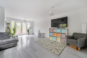Living room with grey seating, TV, rug and patio doors to the garden.