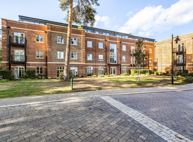 Apartment building with landscaped grounds and paved pathway.
