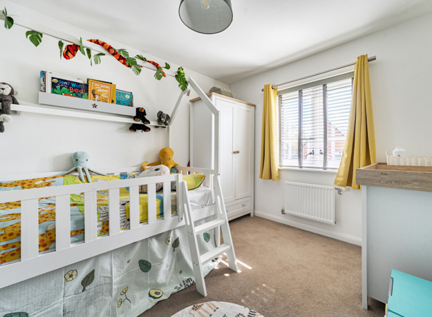 Bedroom with children's bunk bed, wardrobe and window with curtains.