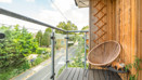 Balcony with glass railing, wooden cladding and a chair.