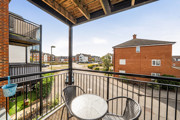 Covered balcony with metal railings and views of neighbouring apartments.