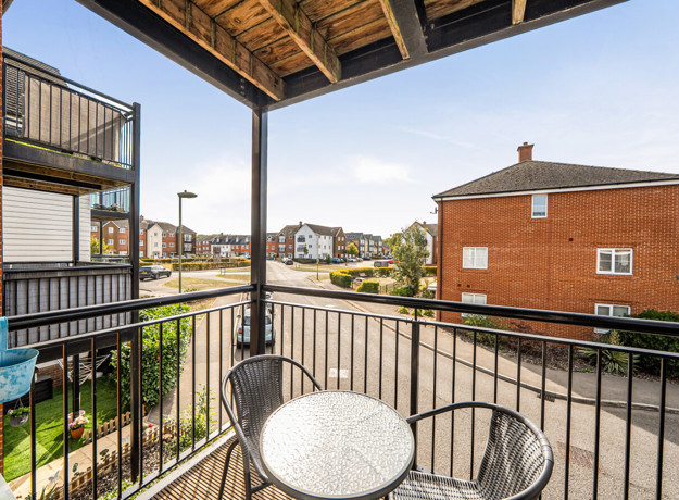 Covered balcony with metal railings and views of neighbouring apartments.