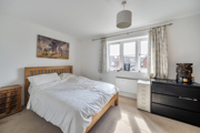 Spacious bedroom with double bed, dresser, and window letting in light.