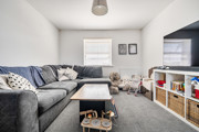 Living room with sofa, coffee table, television, and storage units.