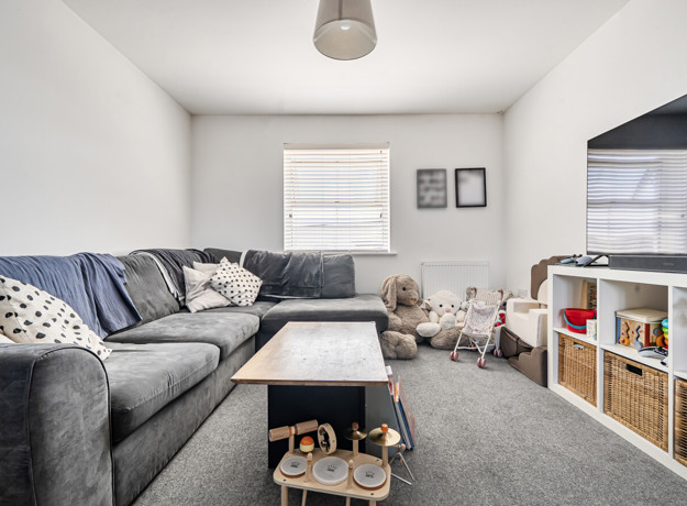 Living room with sofa, coffee table, television, and storage units.