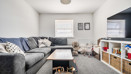 Living room with sofa, coffee table, television, and storage units.