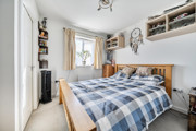Bedroom with double bed, wardrobe, shelving and window.