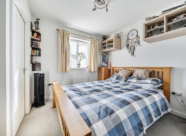 Bedroom with double bed, wardrobe, shelving and window.