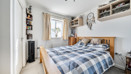 Bedroom with double bed, wardrobe, shelving and window.
