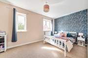 Bedroom with double bed, bedside teables, windows with curtains and patterned feature wall.