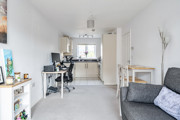 Open-plan living area with sofa, dining table and adjoining kitchen.