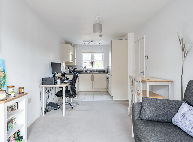 Open-plan living area with sofa, dining table and adjoining kitchen.