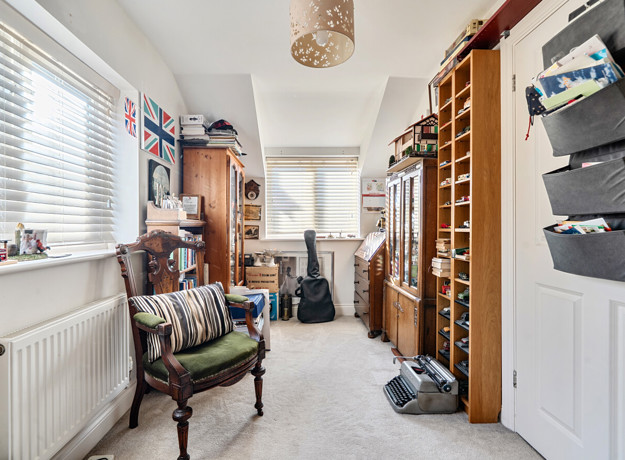 Second bedroom with a wooden chair, bookcase and shelving units.