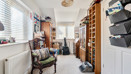 Second bedroom with a wooden chair, bookcase and shelving units.