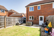 Rear garden with lawn, fence, and brick house exterior view.
