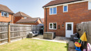 Rear garden with lawn, fence, and brick house exterior view.