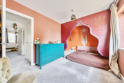 Bedroom with a bed, turquoise chest of drawers and decorative wall mural.