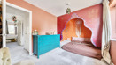 Bedroom with a bed, turquoise chest of drawers and decorative wall mural.