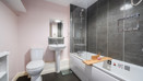 Bathroom with bathtub, wall tiles, toilet and pedestal sink.