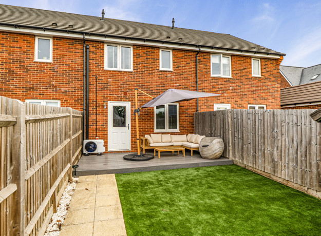 Rear garden with lawn, patio seating area and fenced boundaries.