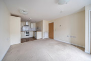 Open-plan living area with fitted kitchen and carpeted floor.