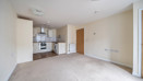 Open-plan living area with fitted kitchen and carpeted floor.