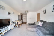 Living room with corner sofa, television and dining area leading to a kitchen.