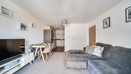 Living room with corner sofa, television and dining area leading to a kitchen.